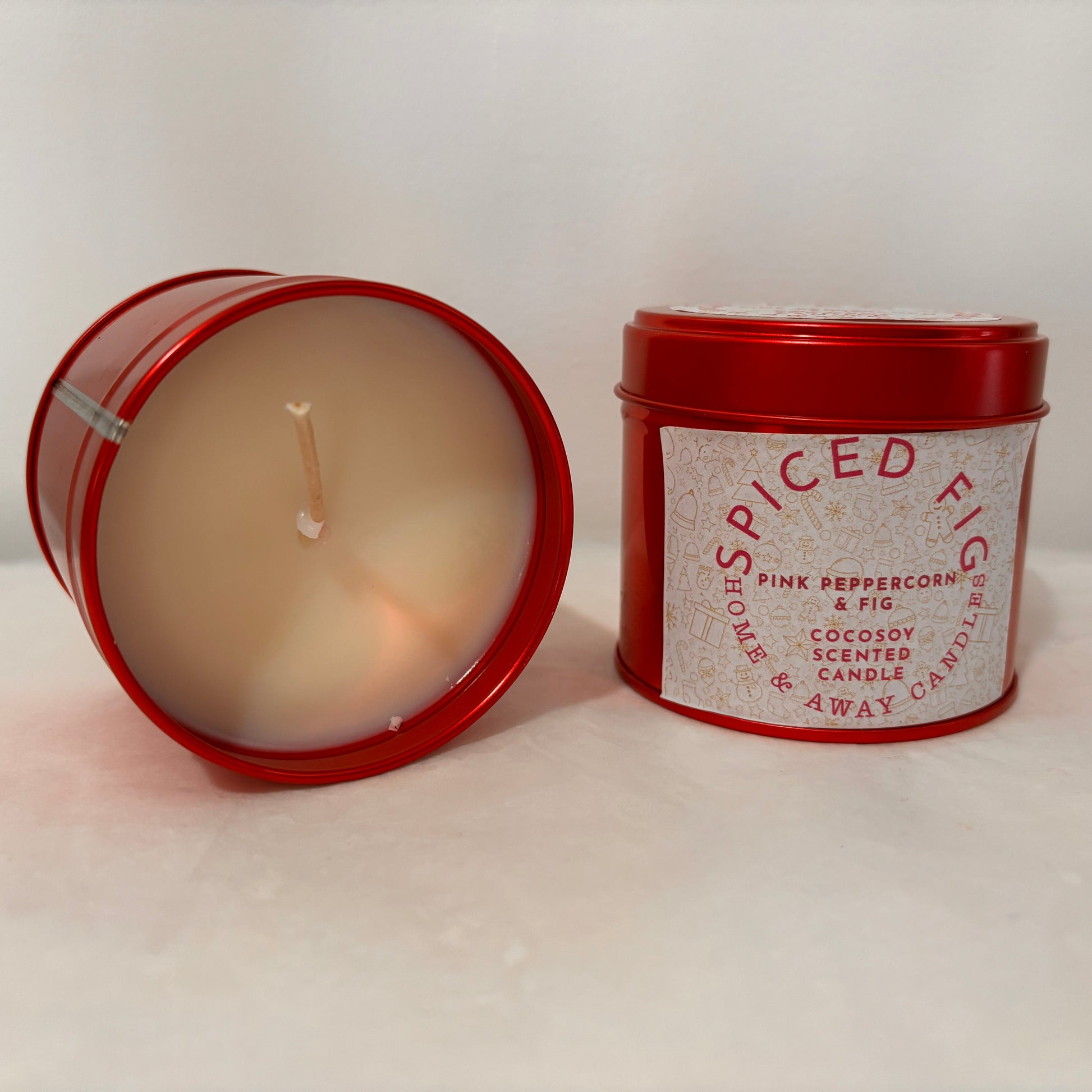 Candle in a red tin with a label on a white surface