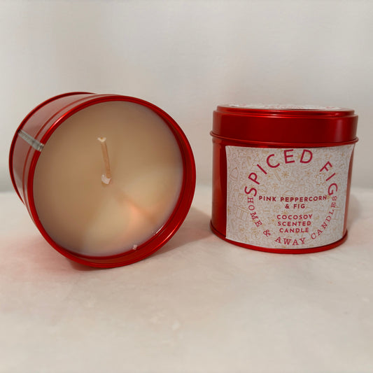 Candle in a red tin with a label on a white surface