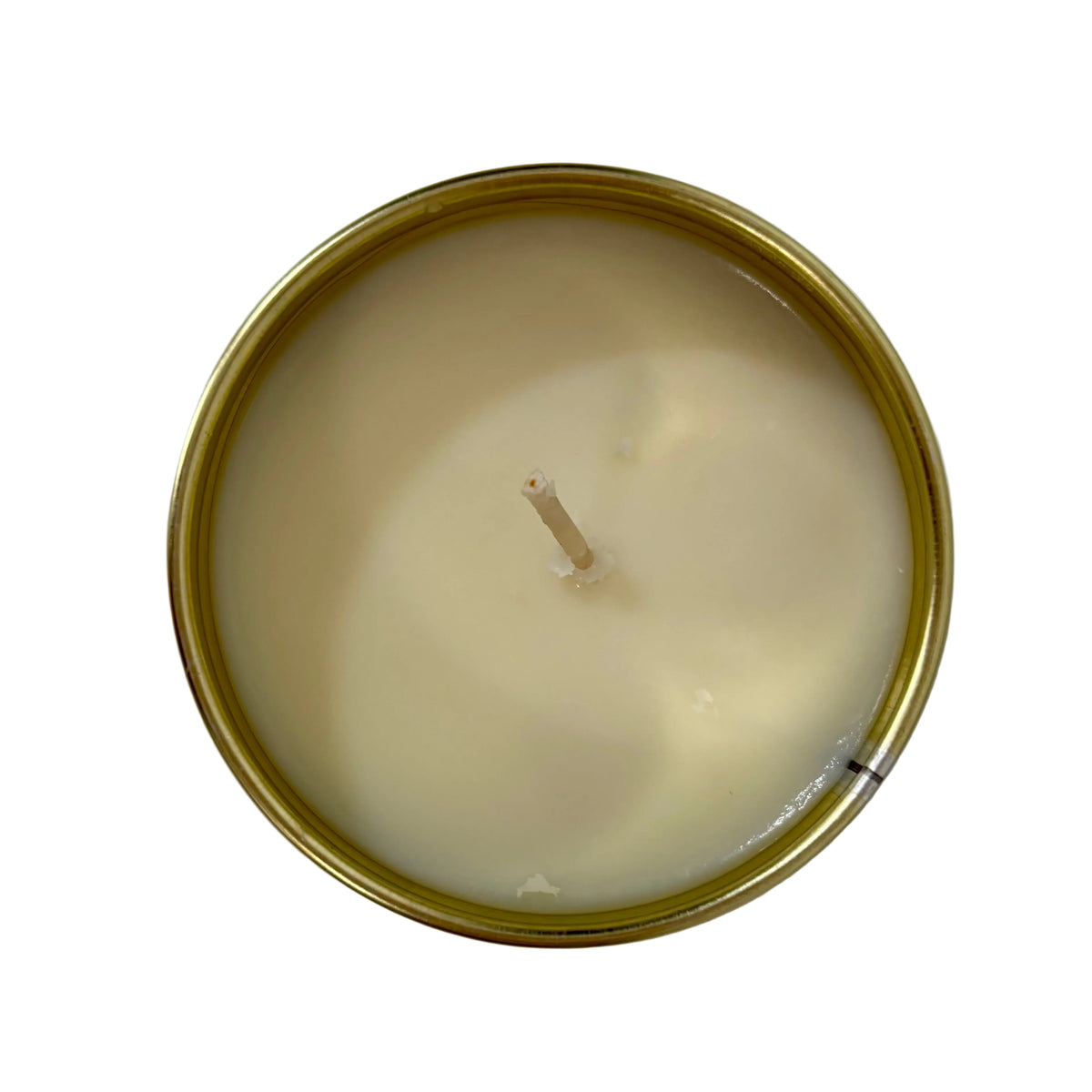 Top-down view of a single-wick candle in a round gold metal tin, filled with creamy off-white wax, set against a plain light background.