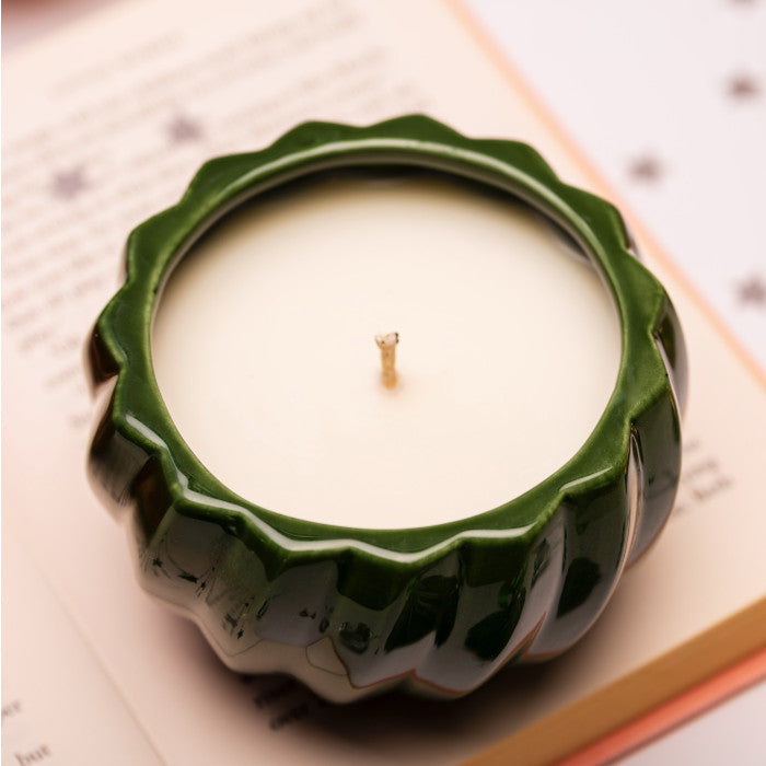 Home-away.co.uk green ceramic Christmas bauble candle with a ribbed design and white wax, viewed from above.